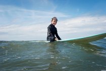 Jeune garçon assis sur une planche de surf en mer — Photo de stock
