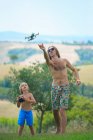 Pai e filho voando avião de controle remoto, ao ar livre — Fotografia de Stock