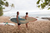 Two men holding surfboards on beach — Stock Photo