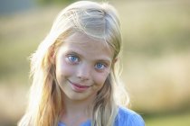 Portrait of young smiling girl with blue eyes in field — Stock Photo