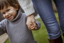 Обрезанное изображение улыбающейся девушки, держащей матерей за руку — стоковое фото