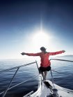 Woman on bow of sailing boat with arms outstretched — Stock Photo