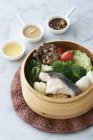 Bamboo steamer of fresh fish and vegetables with condiments — Stock Photo