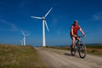 Mountain biker at a wind farm. — Stock Photo