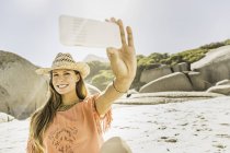 Donna con cappello di paglia che porta smartphone sellfie sulla spiaggia, Città del Capo, Sud Africa — Foto stock