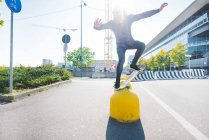 Молодий чоловік міський скейтбордист балансує на вершині жовтого болларда — стокове фото
