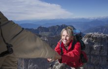Scalatore di sesso maschile che aiuta la sua compagna a raggiungere la cima di una montagna, Dolomiti, Italia — Foto stock