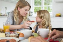 Mother offering daughter some food at home — Stock Photo