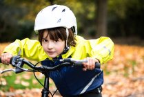 Мальчик в велосипедном шлеме на велосипеде смотрит в камеру — стоковое фото