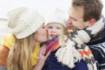 Mid adult parents kissing their daughter on cheek at coast — Stock Photo