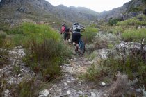 Giovane coppia spingendo mountain bike in montagna — Foto stock