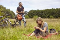 Pareja con bicicletas de picnic en el campo rural - foto de stock