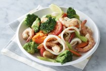 Plato de langostinos, calamares y verduras - foto de stock