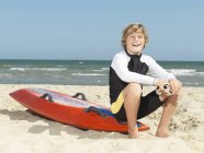 Retrato de garotinho confiante (salva-vidas de surfe infantil) sentado na prancha de surf, Altona, Melbourne, Austrália — Fotografia de Stock
