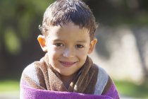 Портрет мальчика с мокрыми волосами, завернутыми в полотенце в саду — стоковое фото