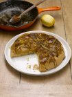 Яблочный пирог татин с кастрюлей и лимоном на столе — стоковое фото