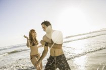 Femme adulte moyenne portant un bikini jouant avec son petit ami sur la plage, Cape Town, Afrique du Sud — Photo de stock