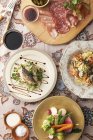 Пищевые тарелки с рыбой, овощами и нарезанным мясом на столе — стоковое фото