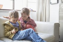 Dois irmãos pequenos usando smartphone em casa — Fotografia de Stock