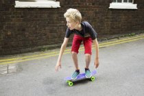 Мальчик катается на доске на пенни на улице — стоковое фото