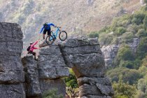 Mountain biking couple climbing rock formation — Stock Photo