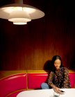 Frau sitzt in holzvertäfelter Bude und blickt aufs Smartphone — Stockfoto