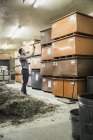 Scientifique photographiant des boîtes empilées dans un entrepôt du centre de recherche sur la croissance végétale — Photo de stock