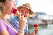Молодая пара смеется и ест мороженое на набережной, Майорка, Испания — стоковое фото
