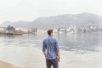 Jeune homme regardant du bord du lac de Côme, Italie — Photo de stock