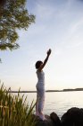Mujer realizando yoga en la orilla del lago - foto de stock