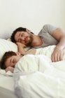 Батько і маленький син сплять в ліжку вдома — стокове фото