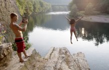 Coppia giovane che fotografa il salto dalla sporgenza di roccia, Amburgo, Pennsylvania, Stati Uniti d'America — Foto stock