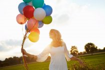 Menina com balões fora ao pôr do sol — Fotografia de Stock