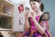 Chica en princesa disfraz de vestido de fantasía jugando con la muñeca - foto de stock