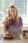Menina degustação bolo geada na cozinha — Fotografia de Stock