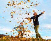Pai e filho brincando em folhas de outono — Fotografia de Stock