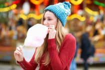 Молодая женщина ест сладкую нить на ярмарке, на открытом воздухе — стоковое фото
