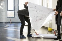 Architect picking up blue prints for clients in new office building — Stock Photo