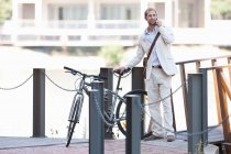 Jeune homme par clôture à chaîne avec vélo sur téléphone portable — Photo de stock
