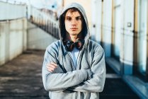 Man wearing hooded top and headphones, arms crossed looking at camera — Stock Photo