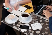 Empresários no café, homem usando laptop e mulher escrevendo — Fotografia de Stock