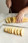 Woman slicing bread with nuts on kitchen counter — Stock Photo