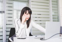 Деловая женщина за рабочим столом смотрит в ноутбук — стоковое фото