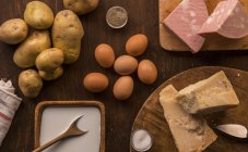 Vista superior de alimentos crudos y preparados, parmesano, leche, huevos y patatas - foto de stock