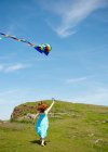 Вид сзади на девушку, бегущую с воздушными змеями в поле — стоковое фото