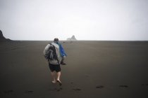 Человек, гуляющий по пляжу Карекаре, Карекаре, Новая Зеландия — стоковое фото