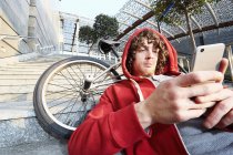 Человек сидит на ступеньках с BMX с помощью смартфона — стоковое фото