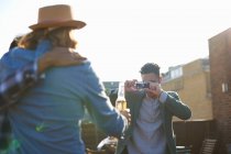 Молодой человек фотографирует друзей мужчин на вечеринке на крыше — стоковое фото
