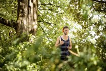 Молодой человек в наушниках бегает в лесу — стоковое фото