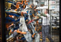 Trabajador manipulación de piezas de automóviles en la fábrica de automóviles - foto de stock